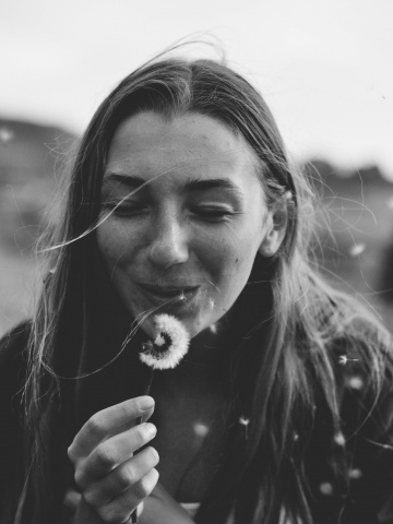 girl blowing on a dandelion